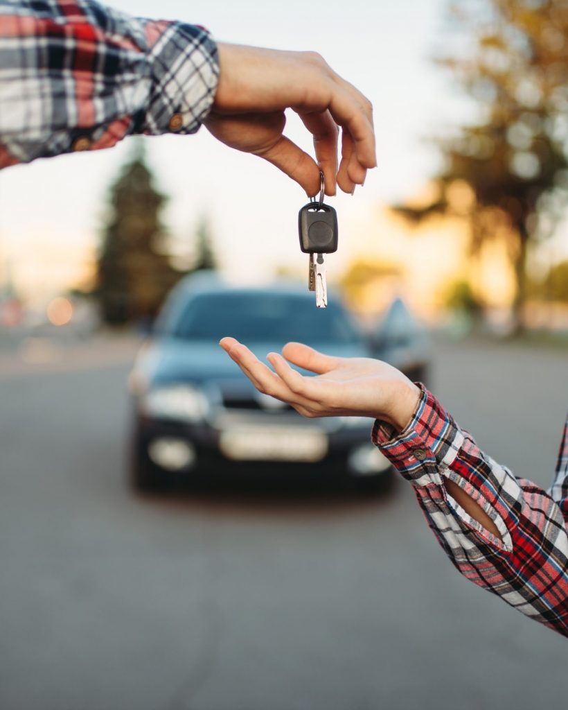 Male driving teacher gives the keys to female student after exam, successful end of car school concept. Test for drivers, automobile course