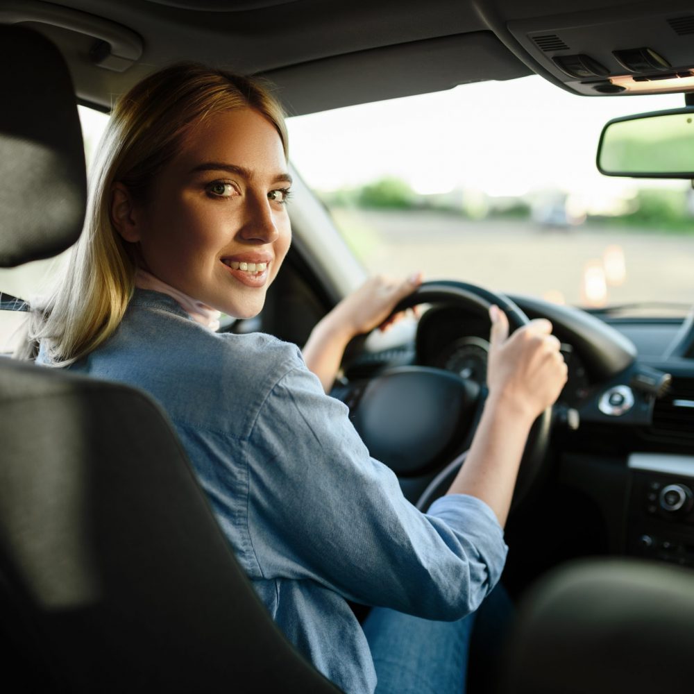 Smiling female student in the car, lesson in driving school. Man teaching lady to drive vehicle. Driver's license education