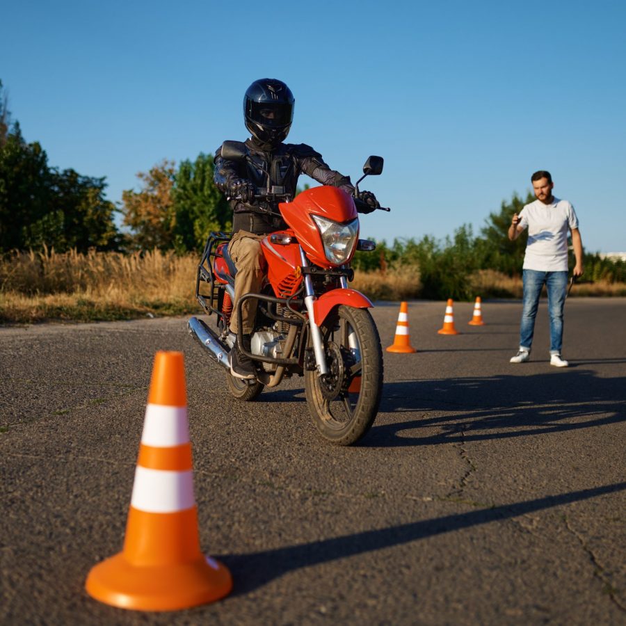 Male student in helmet and instructor, skill exam in motorcycle school. Training of motorcyclists beginners, biker practicing in motorschool